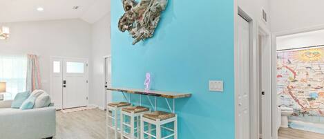 Un salón moderno con una pared de acento azul claro, una mesa de centro de madera y un taburete.