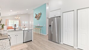 Una cocina moderna con armarios blancos, un refrigerador de acero inoxidable y una pared azul de acento.