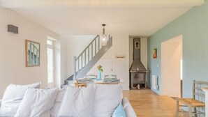 Una sala de estar moderna con un sofá, una escalera, un comedor y una chimenea.