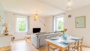 Amplia sala de estar con sofá, mesa de comedor y televisor.