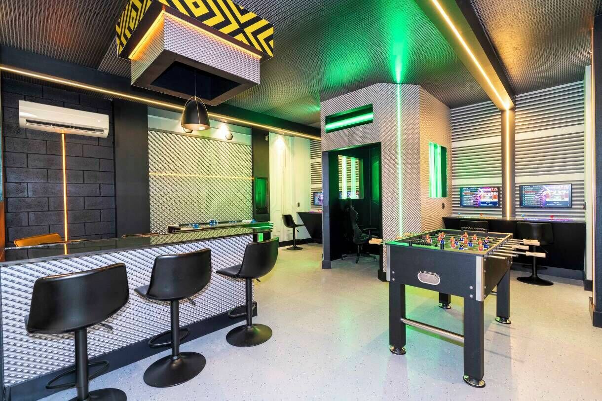 A modern bar area with a foosball table, bar stools, and ambient lighting.