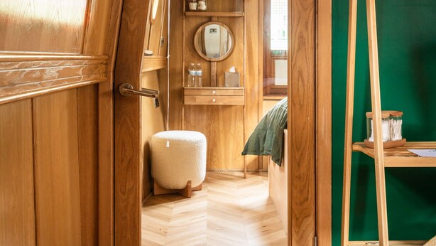 A wooden interior with a door leading to a bathroom, a round mirror, and a shelf with toiletries. - 4* Luxury floating wide beam houseboat moored in Edinburgh city center. (Edinburgh)