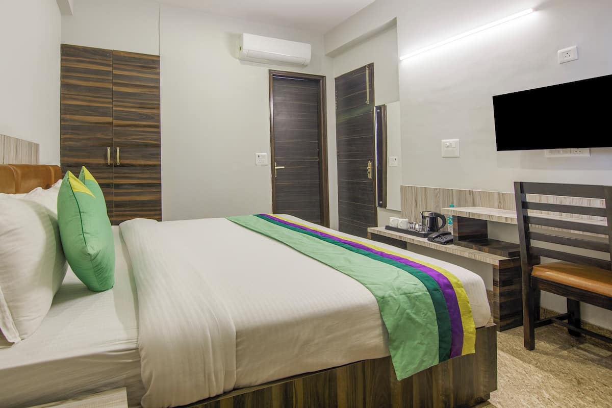 A hotel room with a bed, a desk, a chair, a TV, and a wardrobe.