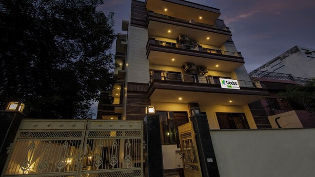 Un edificio de varios pisos con balcones y una entrada protegida por una reja.