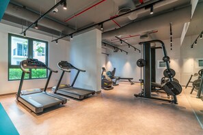 Un gimnasio moderno con cintas de correr, máquinas de pesas y un amplio ventanal que proporciona luz natural.