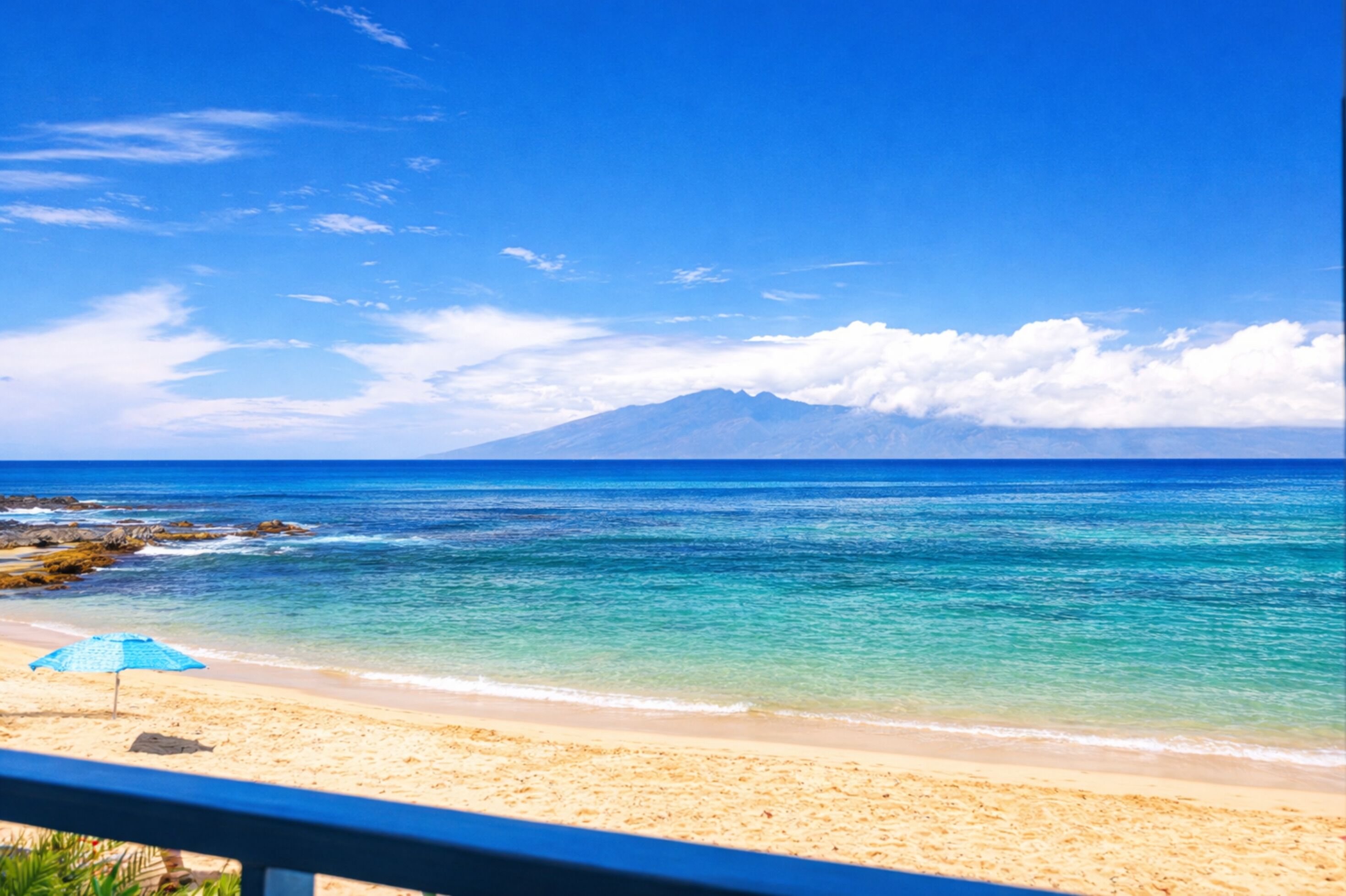 A beach with clear blue water, a sandy shore, and a mountain in the background.
