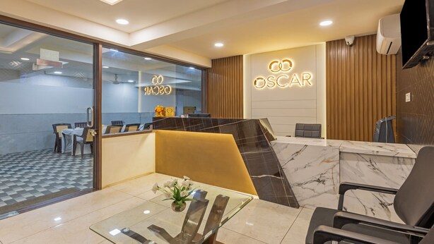 A reception area with a marble counter, a glass table with a vase of flowers, and a sign that reads "OSCAR". - Treebo Oscar (Rajkot)