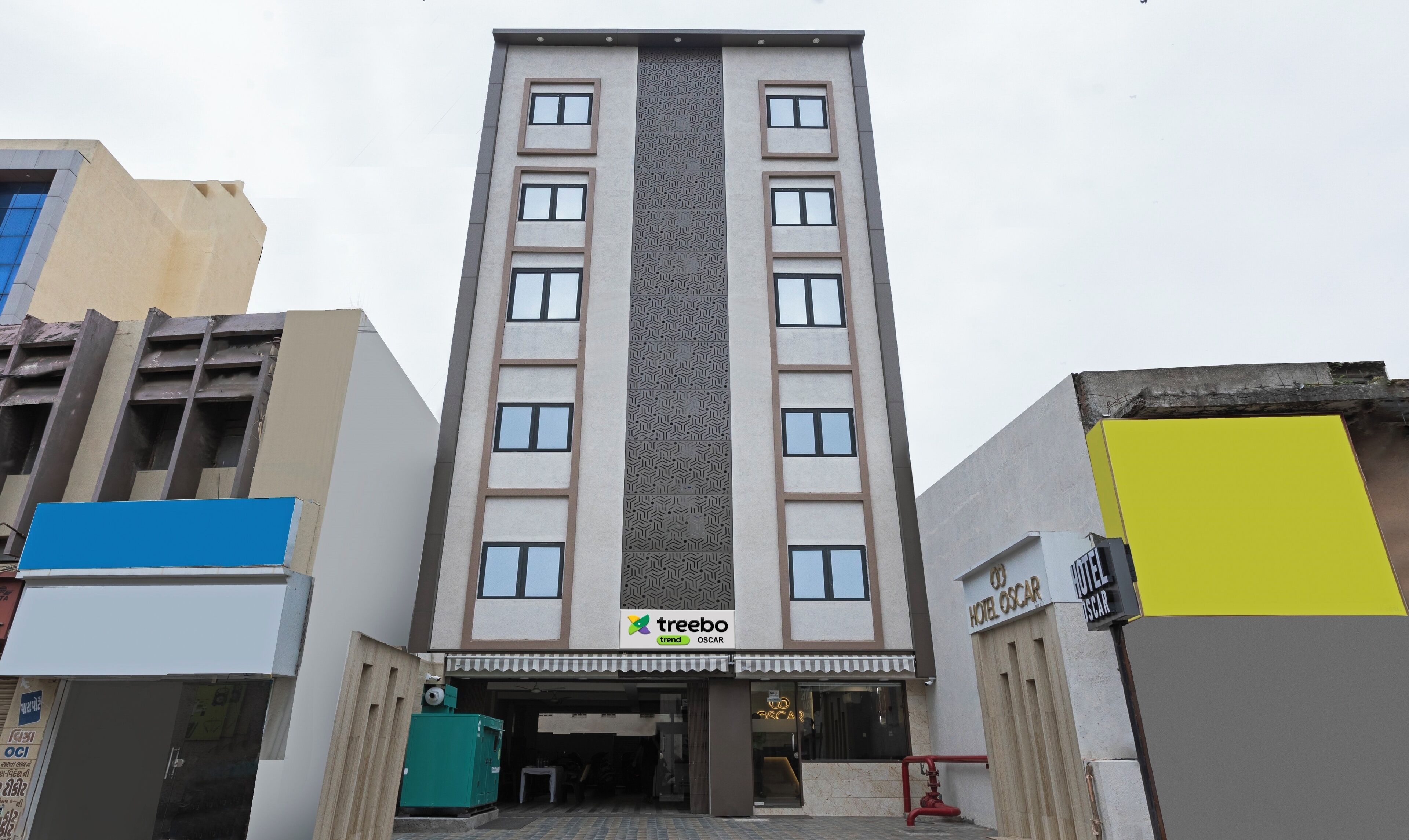 A multi-story hotel with a central vertical feature, a sign for 'treebo trend OSCAR', and a 'HOTEL OSCAR' sign on the right.