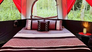 Una habitación con tienda de campaña, una cama, cortinas rojas y luces colgantes.