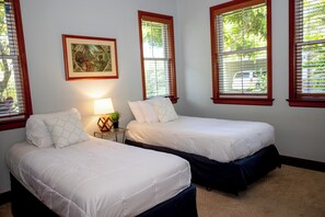 A bedroom with two beds, a nightstand with a lamp, and a framed picture on the wall. - Kolea - Walk to Beach with Pool Access (Waikoloa)
