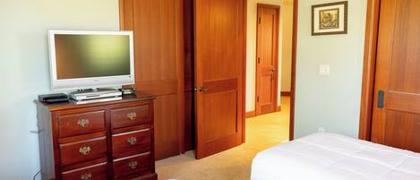 A bedroom with two beds, a dresser, a television, and wooden doors.
