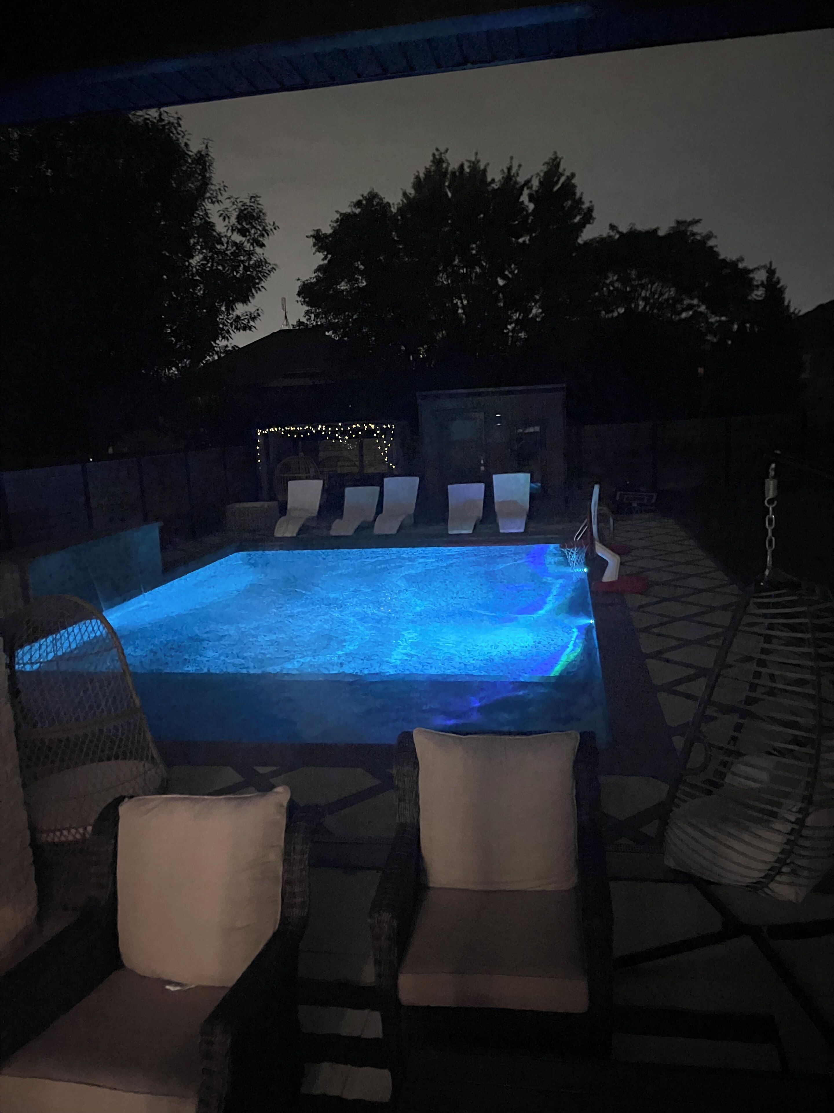 An outdoor pool area with lounge chairs and a hot tub.
