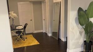 A spacious room with dark wooden flooring, a yellow rug, and a large potted plant. - Modern Spacious 1 bedroom and a den home (Lower Unit) (Windsor)