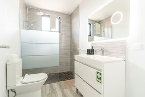 A modern bathroom with a toilet, sink, and shower.