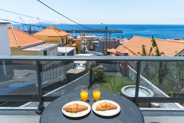 A balcony with a table, two plates of food, and two glasses of orange juice.