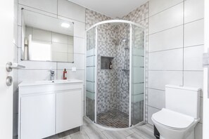 A modern bathroom with a glass-enclosed shower, a white sink, and a toilet.
