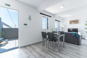 A modern interior with a dining area, a sofa, and a view of the outside. - Casa da Avó 2 by Atlantic Holiday (Caniçal)