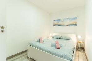 Un dormitori amb llit, almoinades, un quadre i una làmpada de nit.