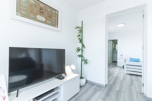 A modern living room with a flat-screen TV, a potted bamboo plant, and a framed nautical chart on the wall.