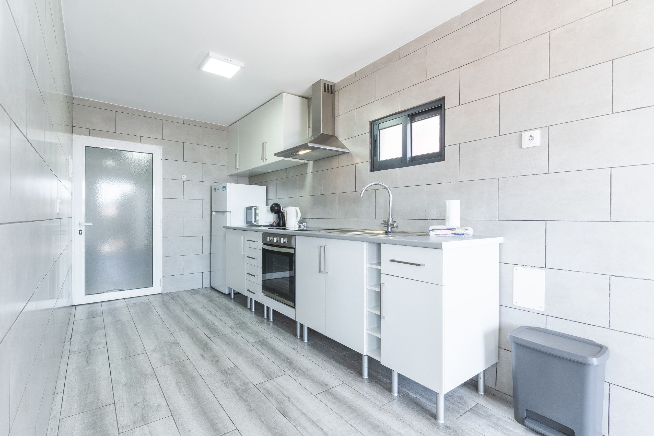 A modern kitchen with white cabinetry, a stainless steel oven, and a built-in microwave.