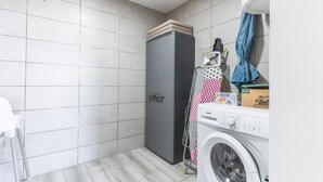 Un espace buanderie comprenant un lave-linge, un sèche-linge et un étendoir.