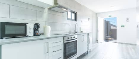A modern kitchen with white cabinetry, a built-in oven, a microwave, and a coffee maker.