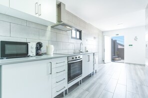 A modern kitchen with white cabinetry, a built-in oven, a microwave, and a coffee maker.
