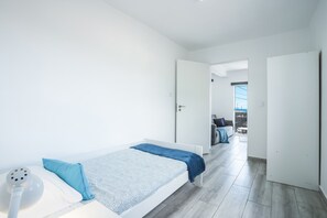 A minimalist bedroom with a single bed, a bedside table, and a power outlet.