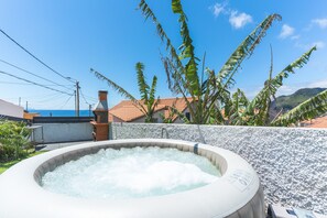 A hot tub with a clear view of the sea and mountains in the background.