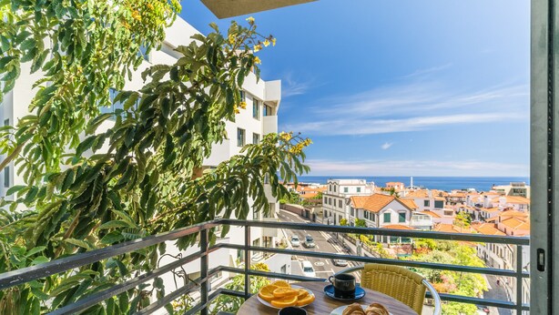 A balcony with a table set for breakfast, overlooking a coastal town. - Yellow Rose by Atlantic Holiday (Funchal)