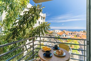 Un balcone con un tavolo apparecchiato per la colazione, con vista su una cittadina costiera.