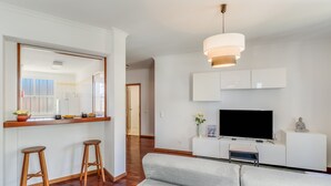 A modern living room with a sofa, a TV, and a dining area with stools and a counter. - Yellow Rose by Atlantic Holiday (Funchal)