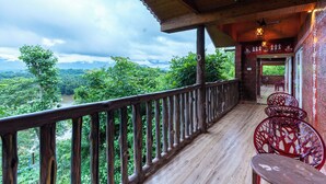 A wooden deck with a railing overlooking a lush green landscape. - Treebo Rock Valley (Ponda)