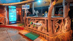 A reception area with a wooden design, a Pepsi refrigerator, and a reception desk. - Treebo Rock Valley (Ponda)