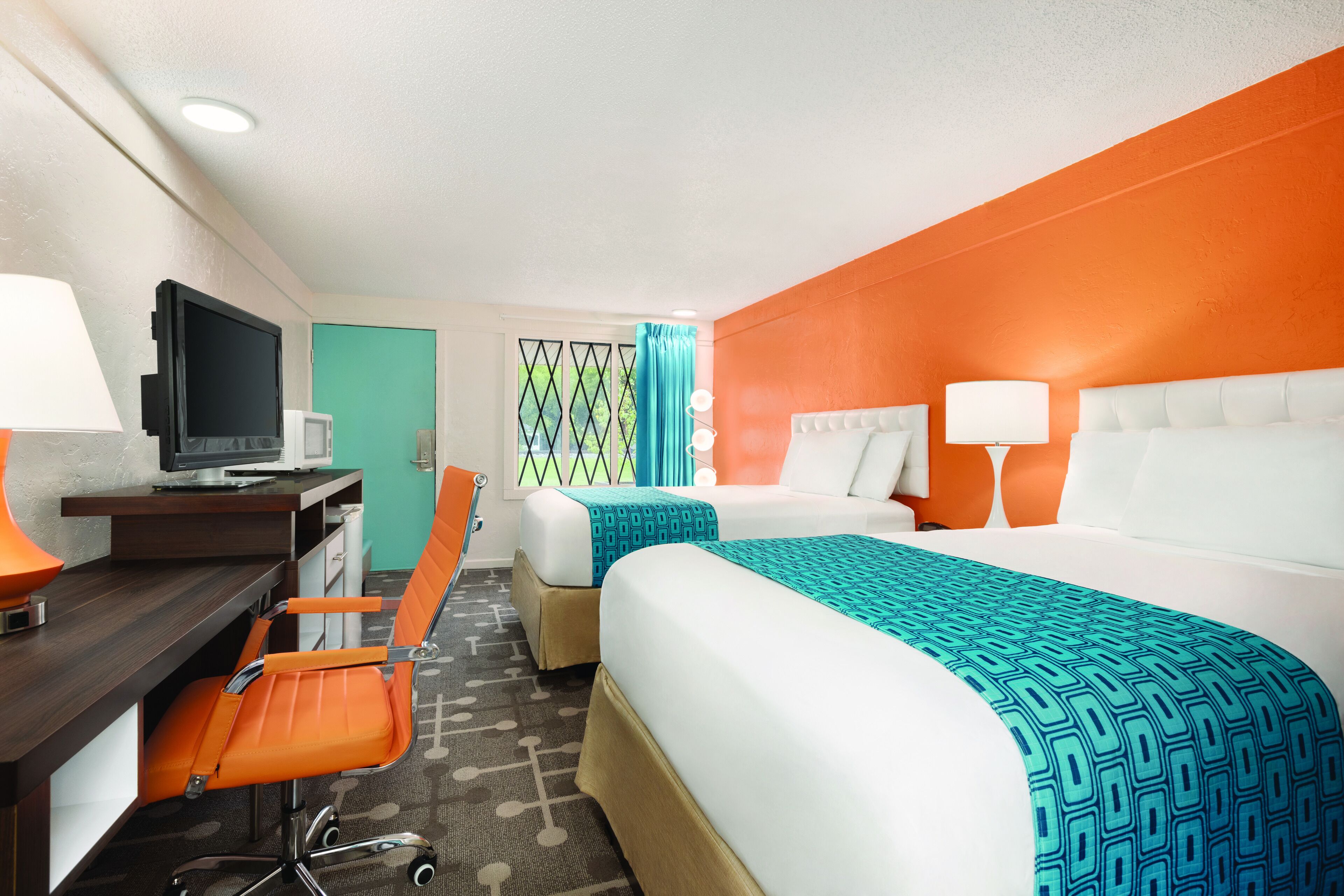 A hotel room with two beds, a desk with a computer, and a chair.