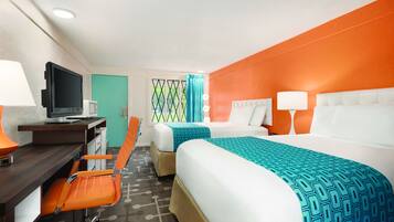 A hotel room with two beds, a desk with a computer, and a chair.