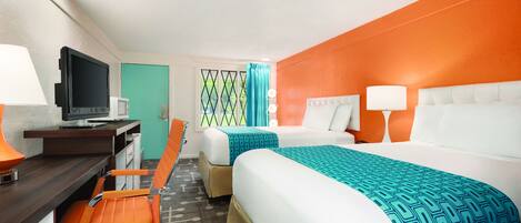 A hotel room with two beds, a desk with a computer, and a chair.