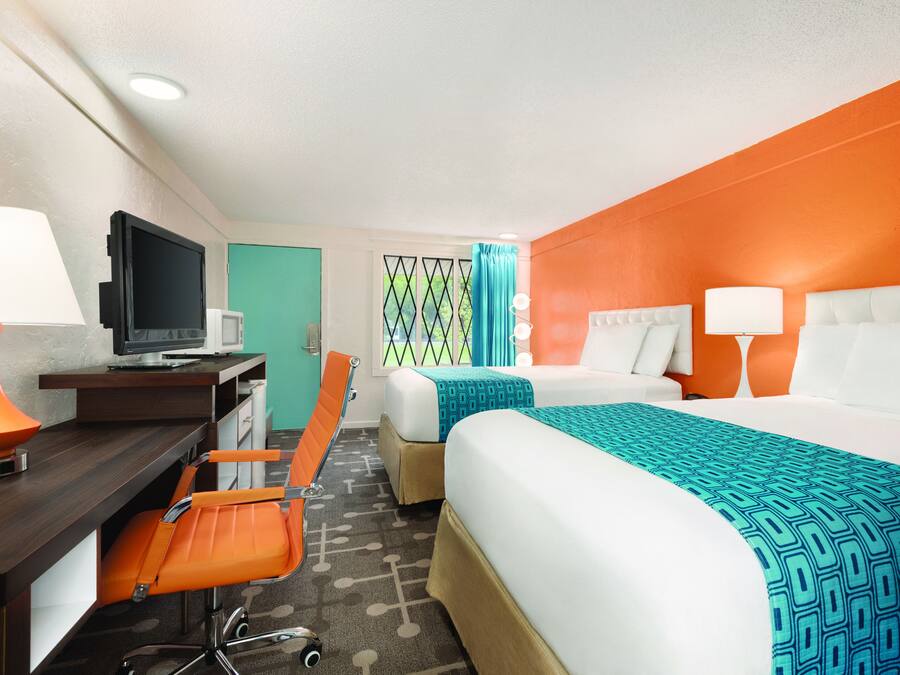 A hotel room with two beds, a desk with a computer, and a chair.