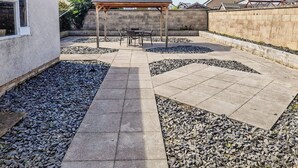 Ein Patio mit Pergola, Sitzgelegenheiten und einem Steinweg.