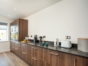Una cocina moderna con armarios de madera, encimera negra y diversos electrodomésticos.