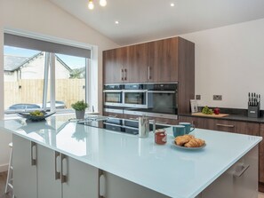 Una cocina moderna con una isla grande, electrodomésticos de acero inoxidable y vistas al patio trasero.