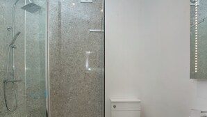 A bathroom with a glass-enclosed shower, a white toilet, and a sink.