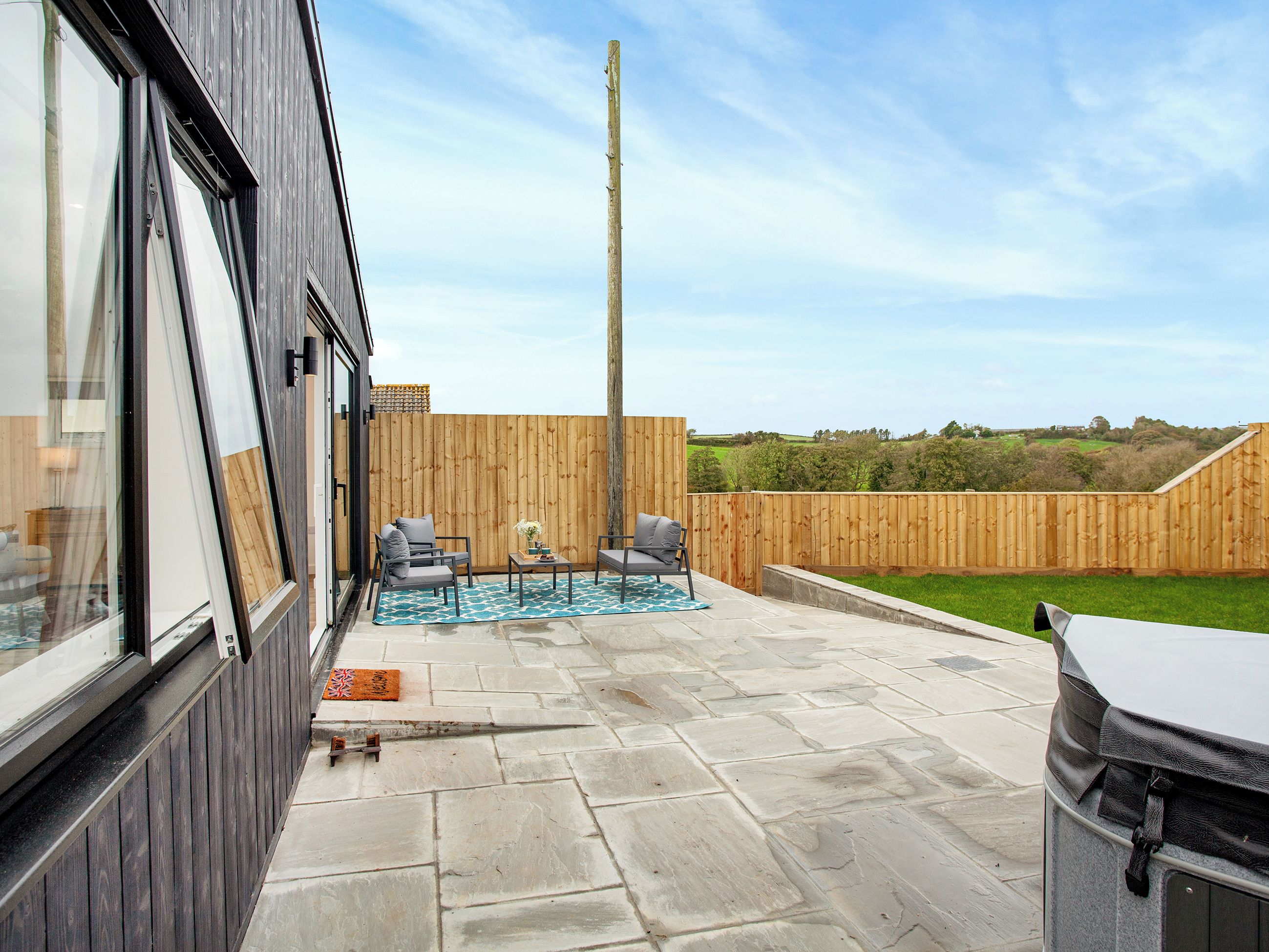 A patio with stone flooring, a wooden fence, and outdoor furniture.