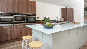 Una cocina moderna con electrodomésticos integrados, una isla central y taburetes de madera.