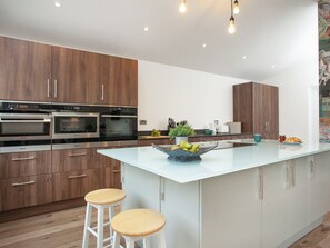 Una cocina moderna con electrodomésticos integrados, una isla central y taburetes de madera.
