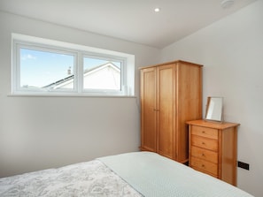 Un dormitorio con una cama, un armario de madera, un espejo y una ventana.
