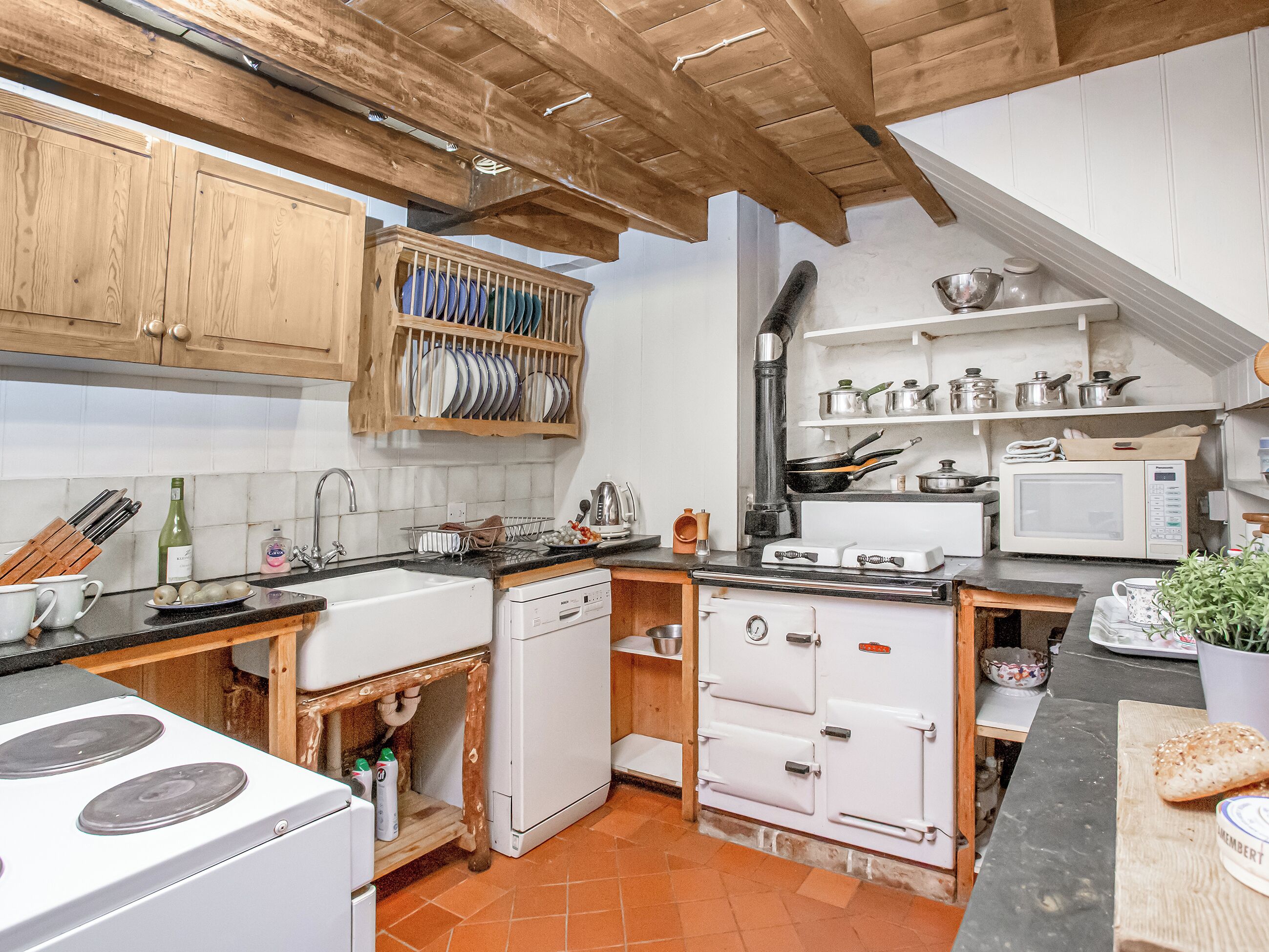 A kitchen with wooden cabinets, a stove, a microwave, and a sink.