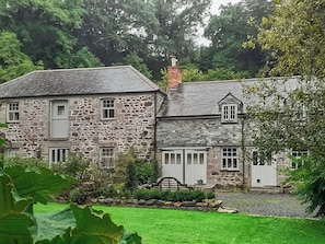 A stone house with a two-story structure, a front porch, and a well-maintained lawn.