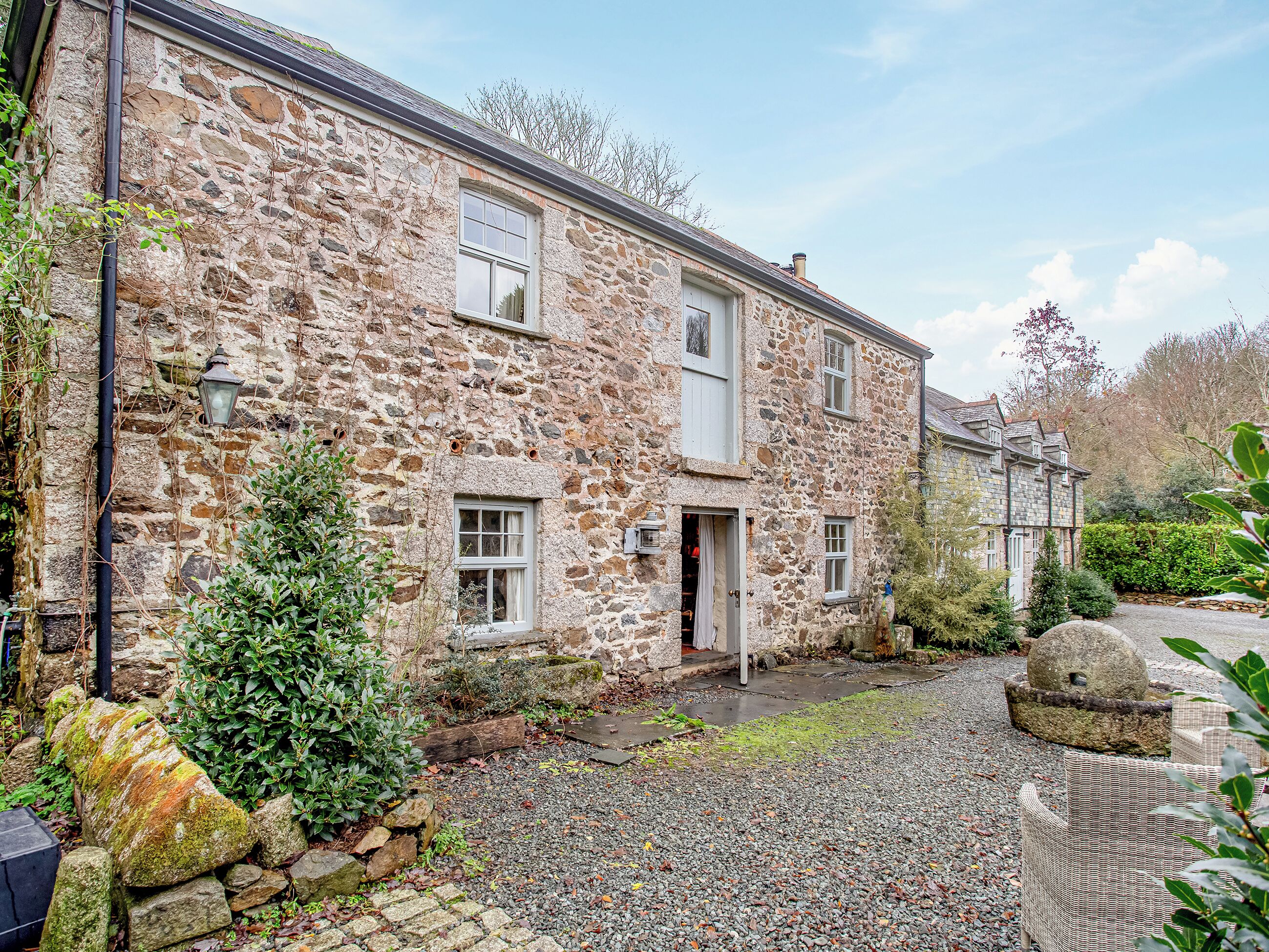 A stone building with a gravel driveway and a small garden area.