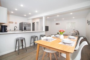 A modern kitchen with white cabinets, stainless steel appliances, and a wooden dining table set for four.